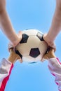 KidÃ¢â¬â¢s and adult`s hands holding football ball together